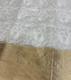 Gold lace fabric with intricate patterns on a white lace background