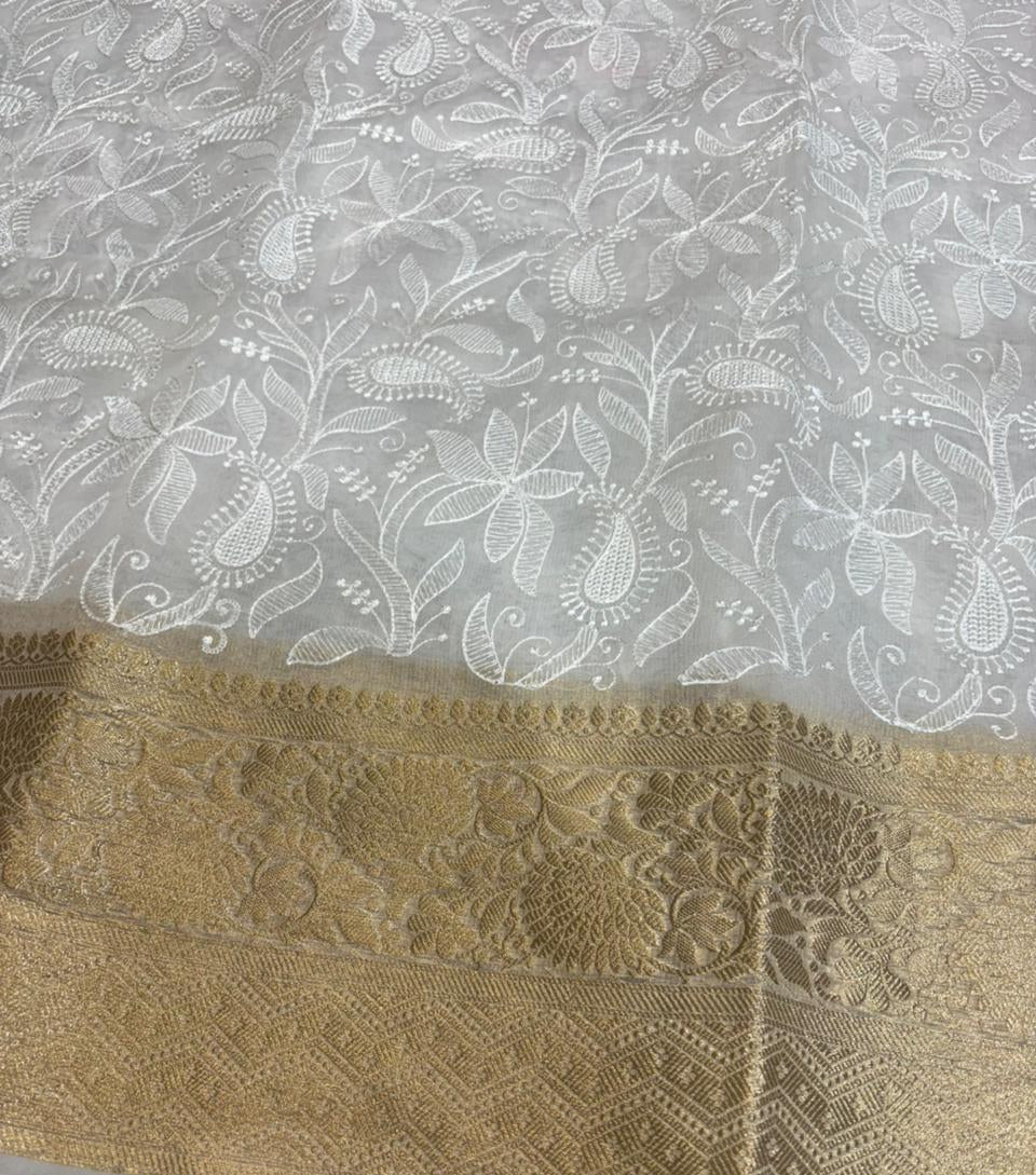 Gold lace fabric with intricate patterns on a white lace background