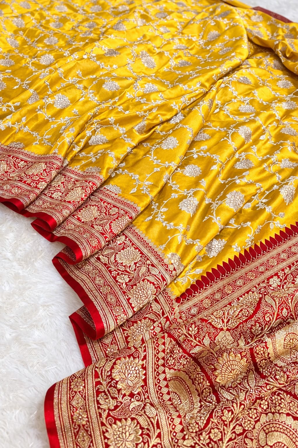 Yellow saree with red and gold border on a white background