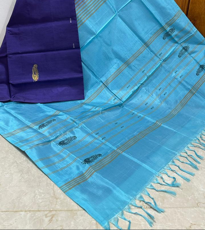 A purple and turquoise blue saree with gold zari stripes and motifs, draped against a wooden door background.