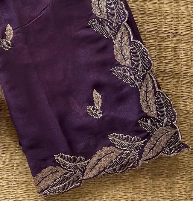 Purple fabric with gold embroidery on a textured surface