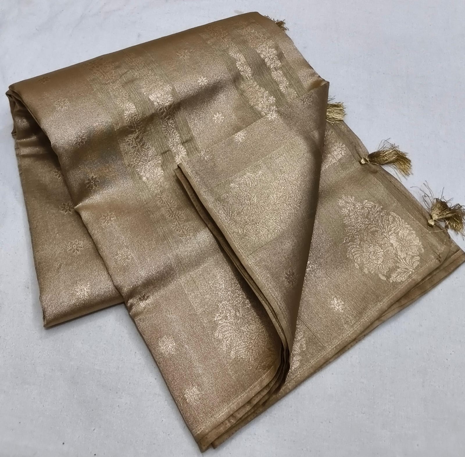 Folded gold fabric with intricate patterns on a light gray background