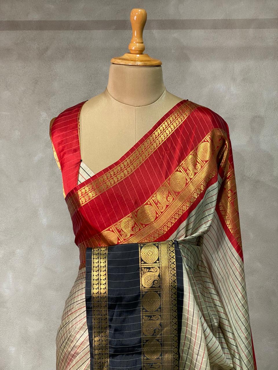 Red and gold saree draped over a mannequin against a gray background