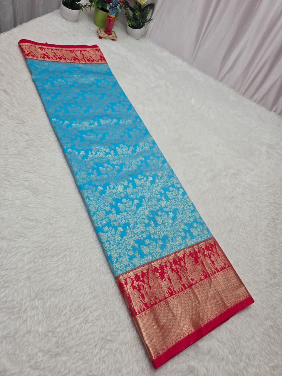 Blue saree with red border on a white surface