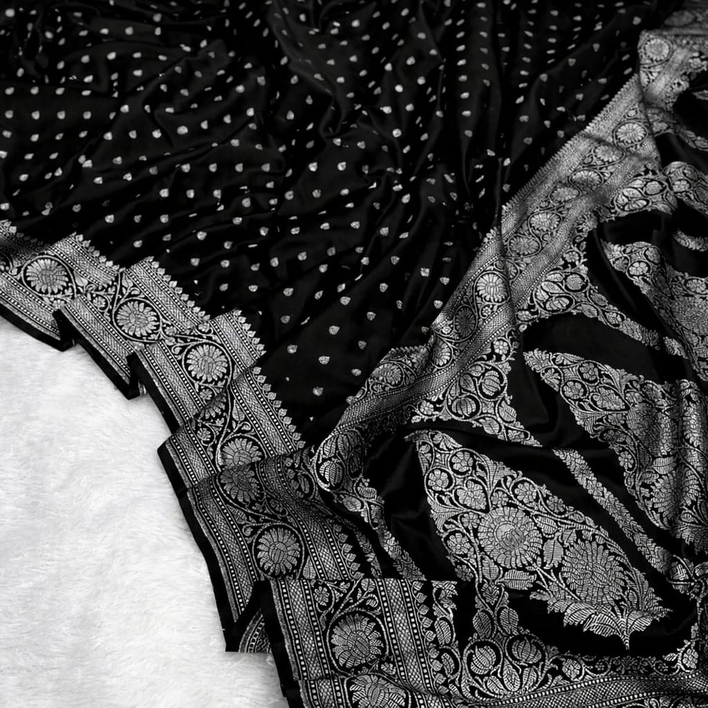 Close-up of black fabric with white polka dots and intricate silver embroidery on a white background