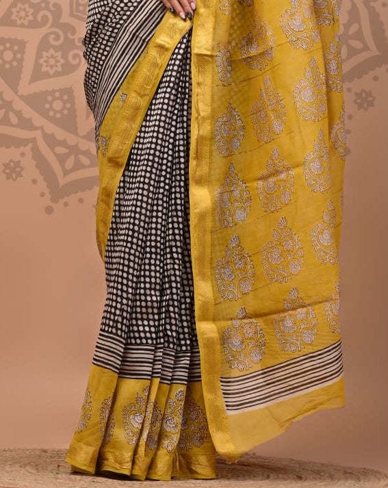 Woman wearing a yellow and black saree with a decorative background