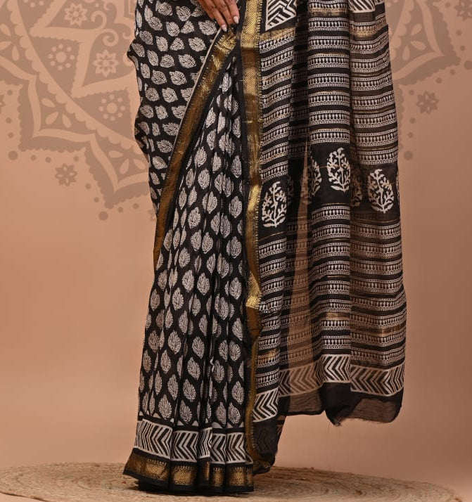 Woman wearing a black and white patterned saree with a decorative background