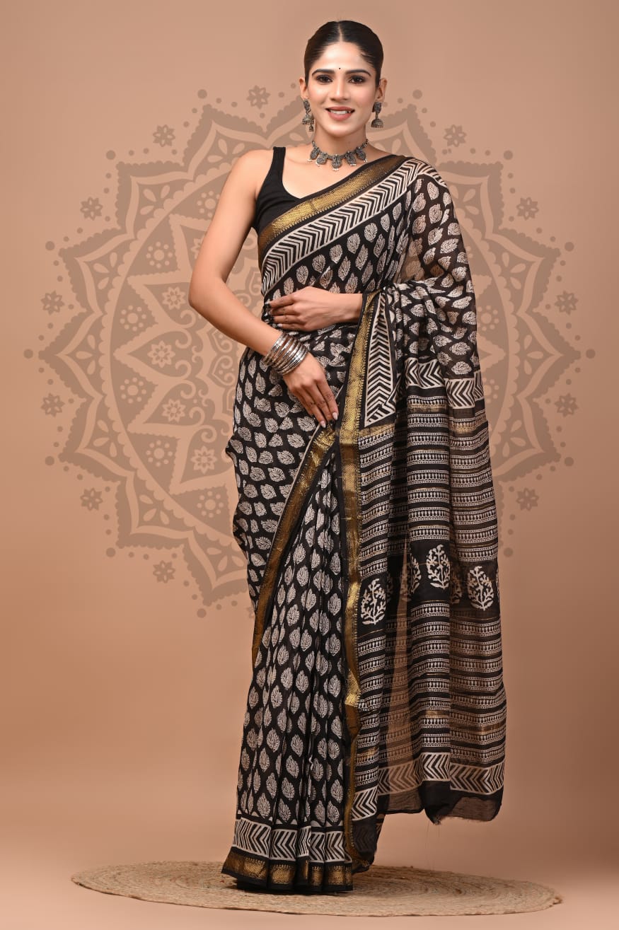 Woman wearing a black and white patterned saree with a decorative background