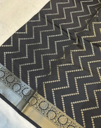 A close-up of a black fabric with a beige zigzag pattern and a decorative beige border.