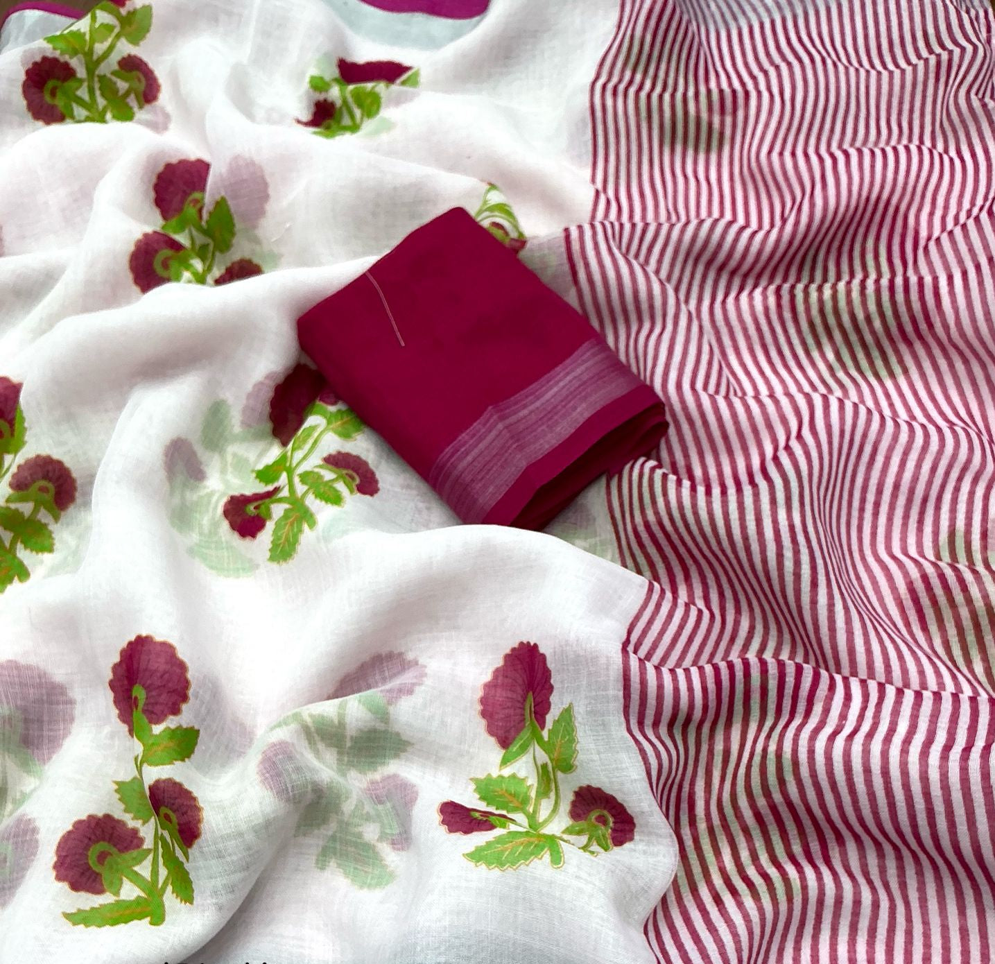 White linen saree with rose prints and a pink border, alongside a matching pink fabric.