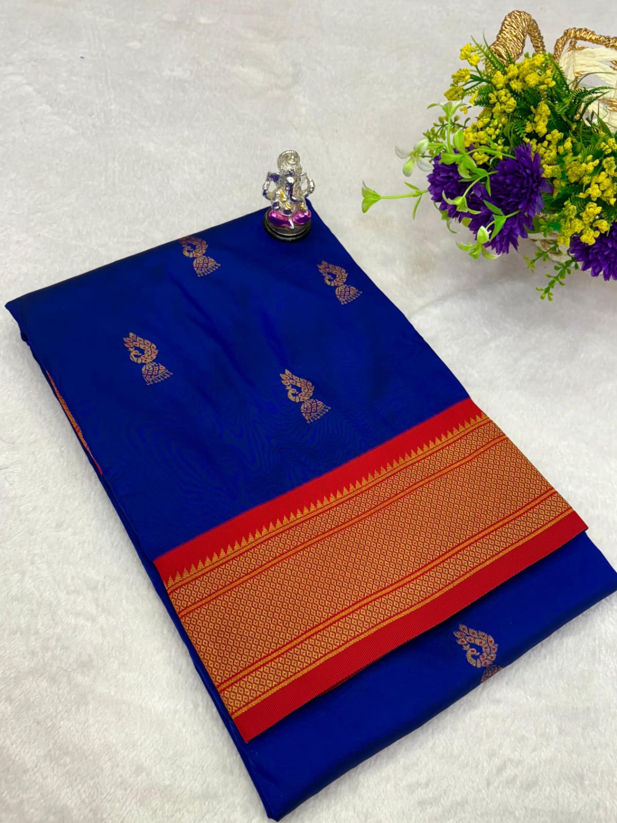 Blue saree with red and orange border on a light gray background