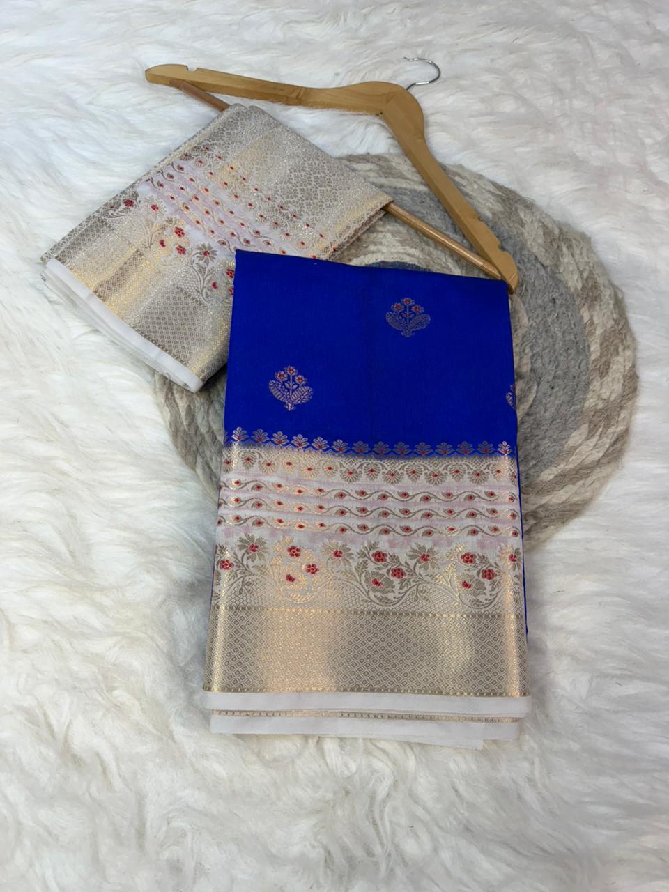 Blue and gold saree with a hanger on a white textured surface