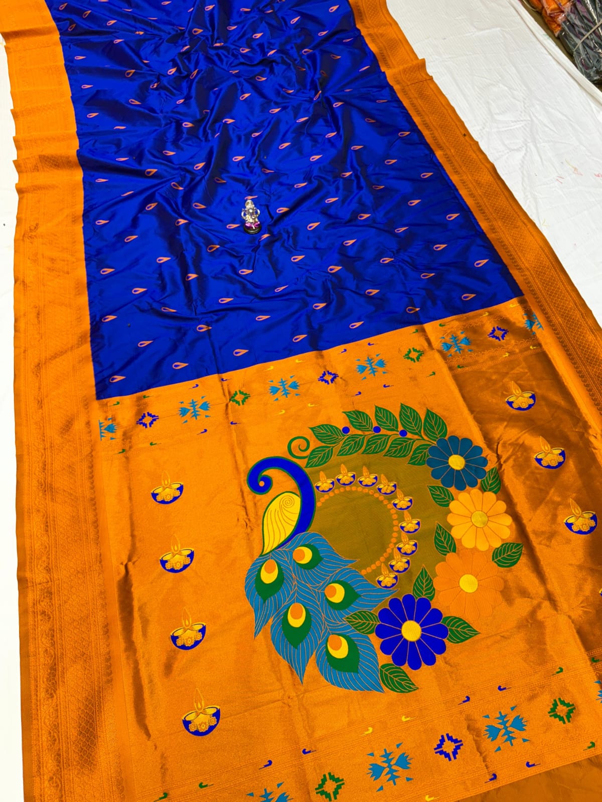 Orange saree with blue border and peacock design on a white background