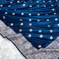 Blue saree with white floral patterns and silver border on a white background