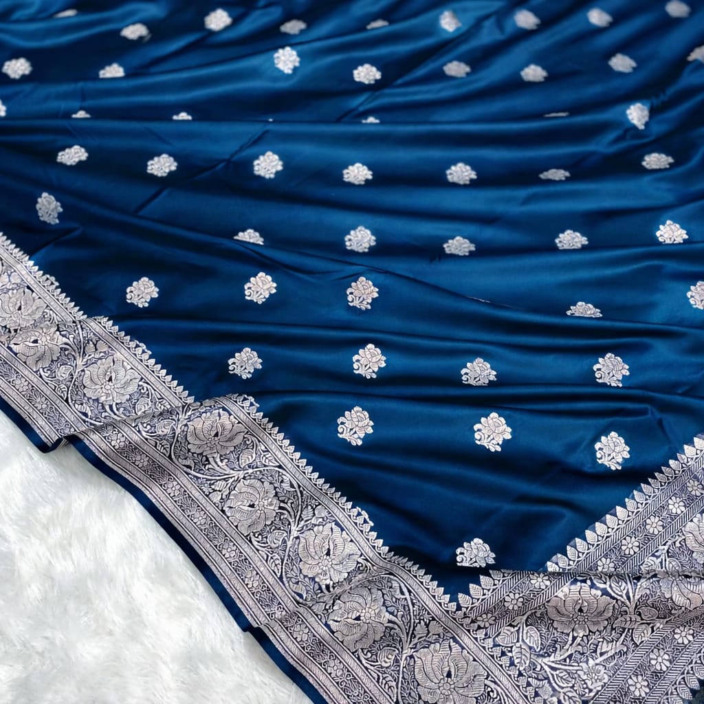 Blue saree with white floral patterns and silver border on a white background