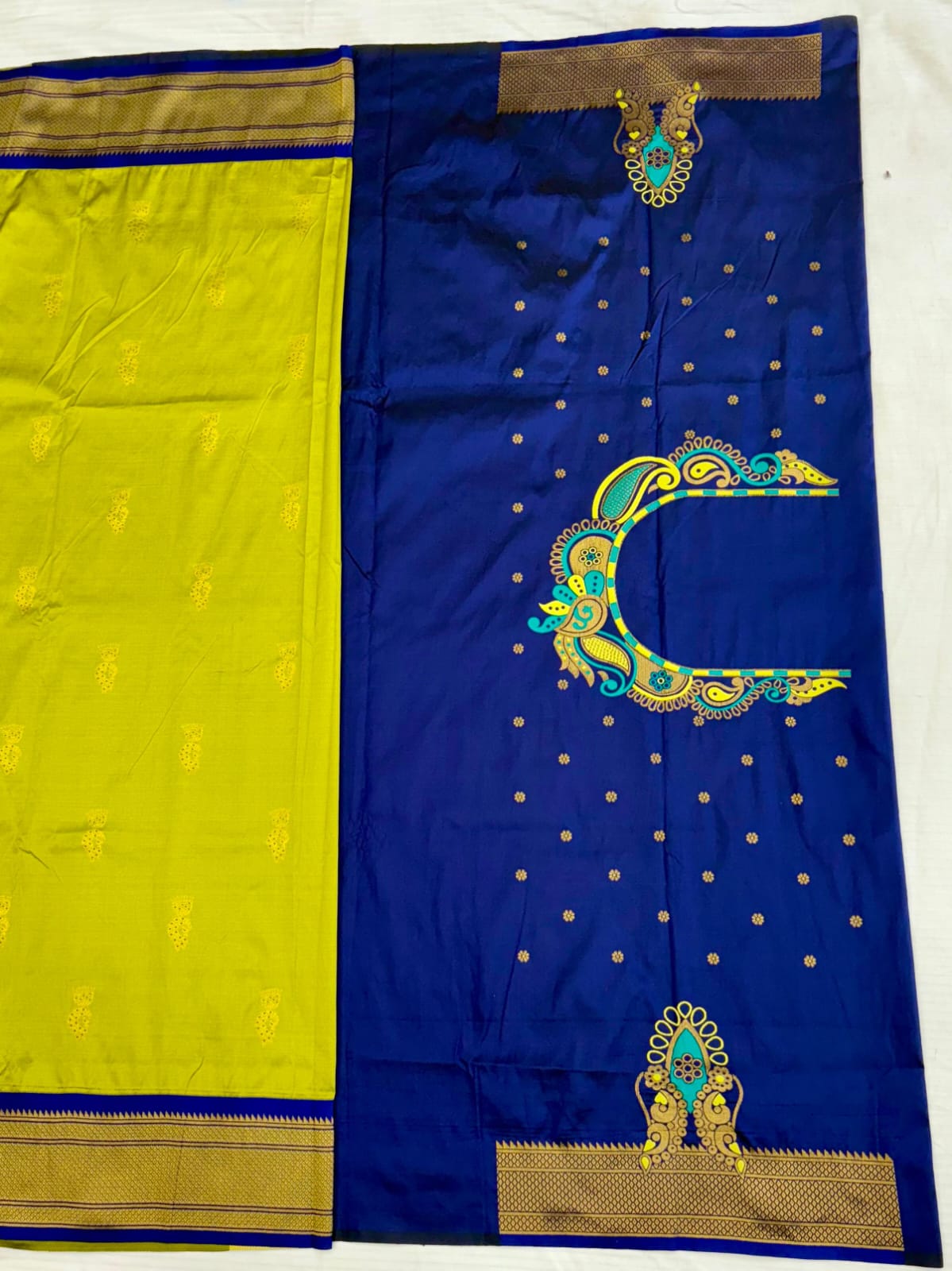 Blue and yellow saree with intricate gold and green patterns on a white background