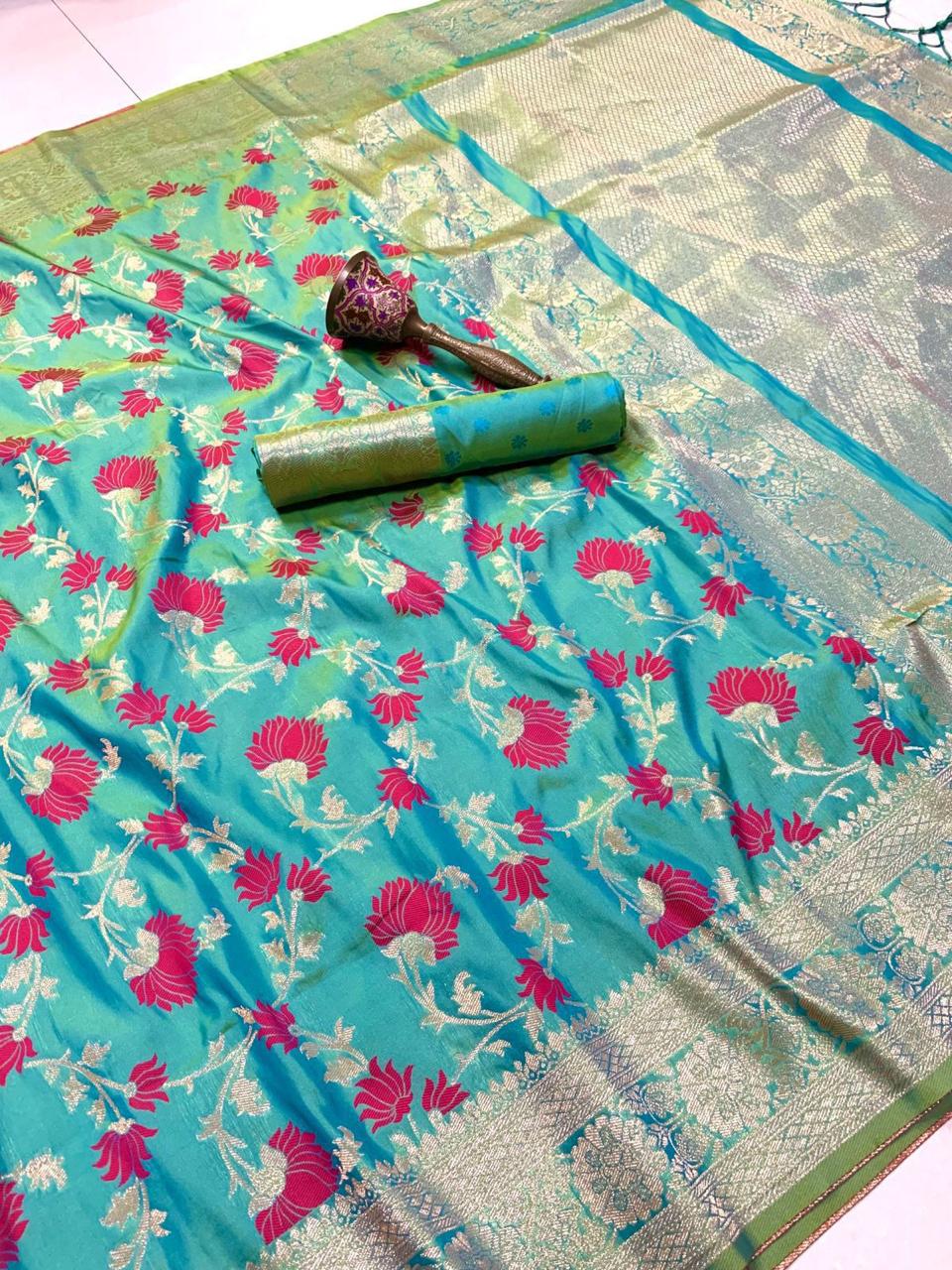 Turquoise saree with pink floral patterns and a decorative roll on a white background