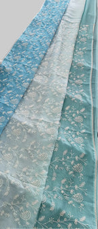 Blue floral-patterned fabric draped over a surface with potted plants in the background.