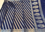 A navy blue saree with silver metallic Banarasi stripes and a wide border featuring silver floral motifs.
