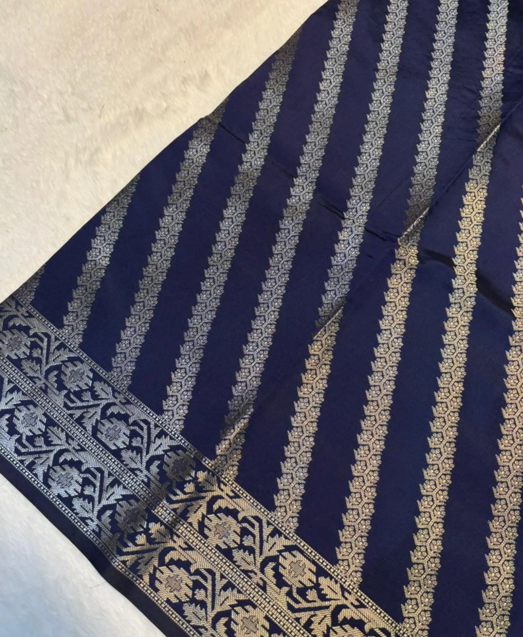 A close-up of a navy blue fabric with vertical metallic gold stripes and an ornate gold border pattern, laid flat on a light textured surface.