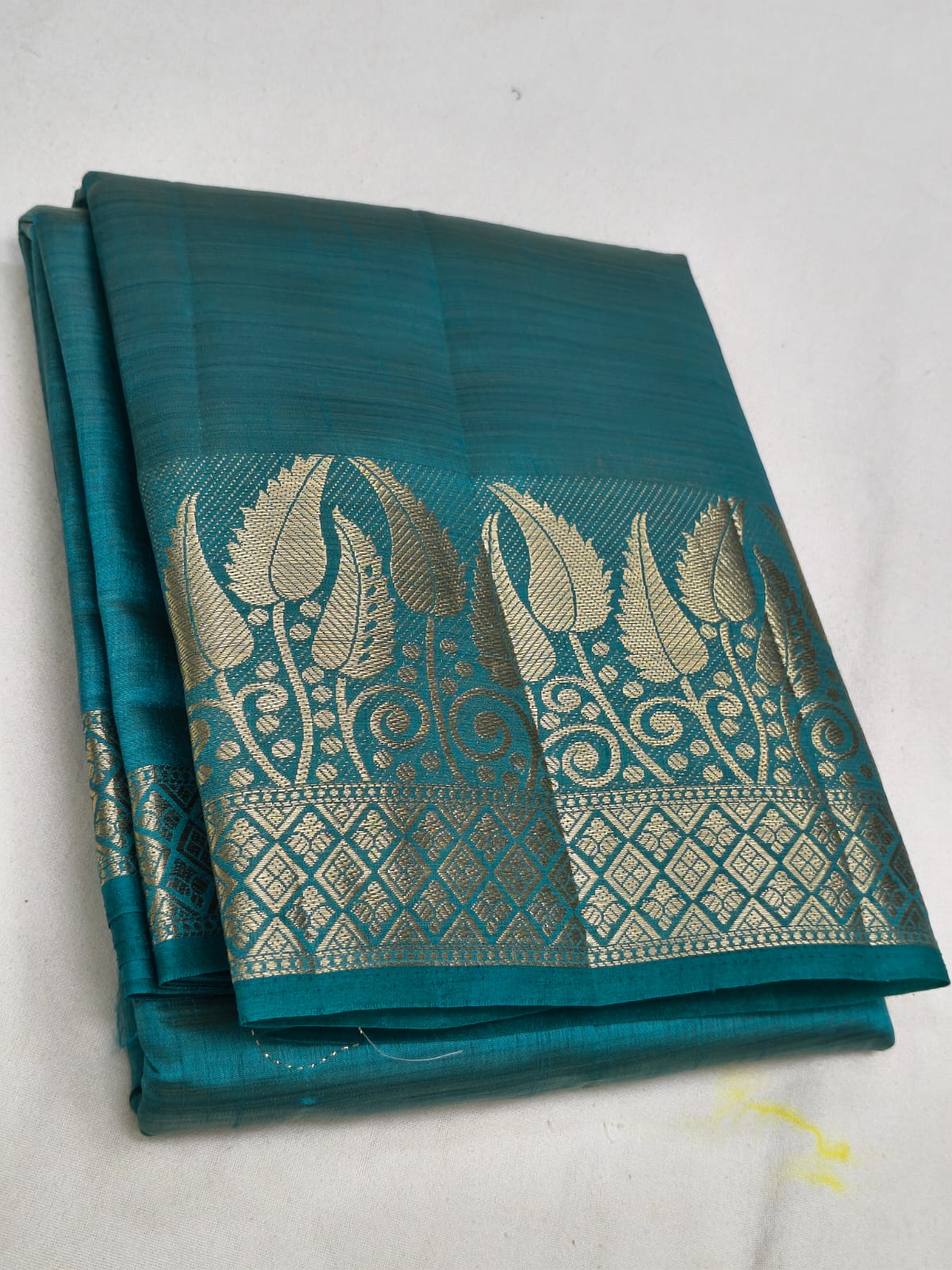Teal saree with silver leaf pattern on a white background