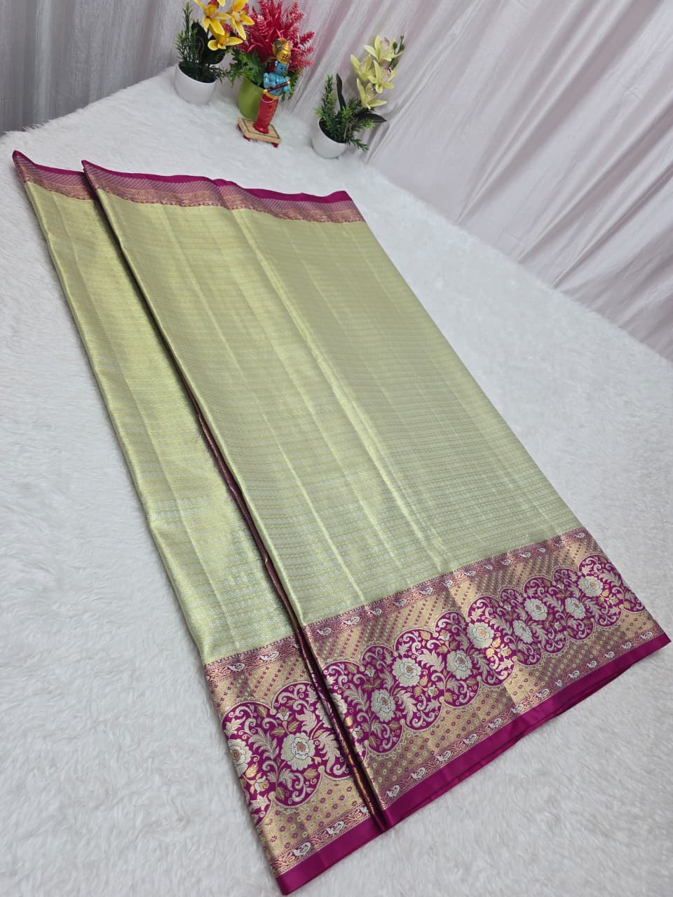 Light green saree with pink and gold border on a white background