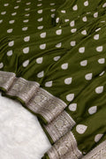 Green fabric with white polka dots and intricate silver border