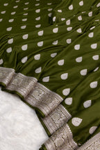 Green fabric with white polka dots and intricate silver border