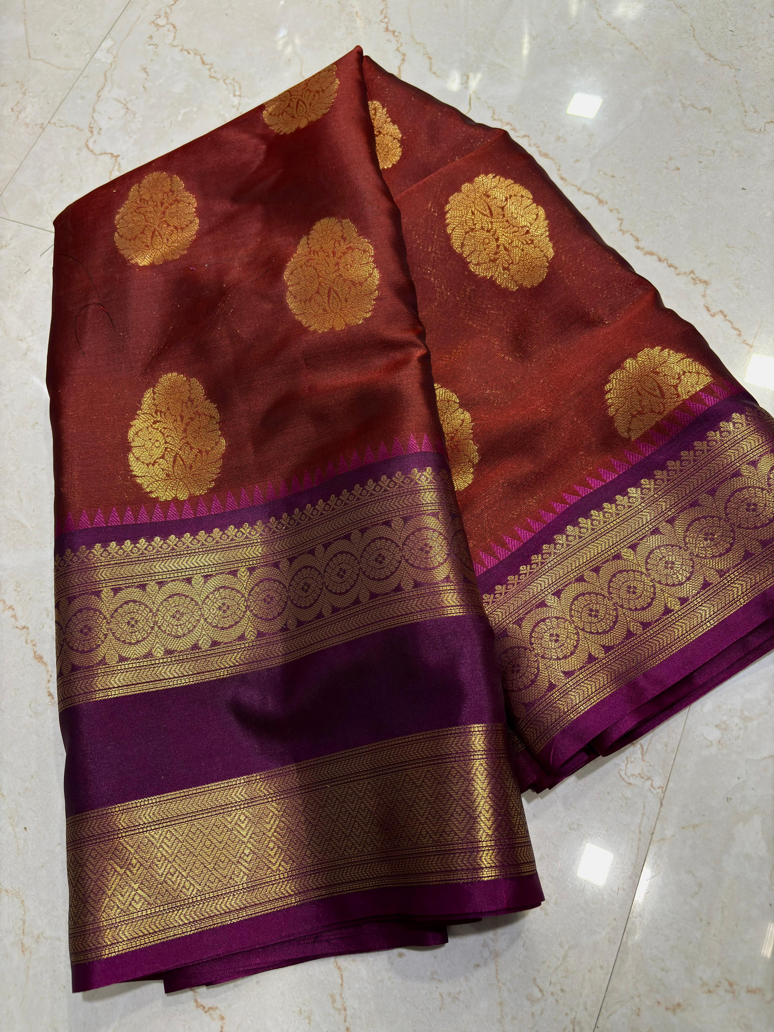Maroon and purple saree with gold patterns on a marble floor