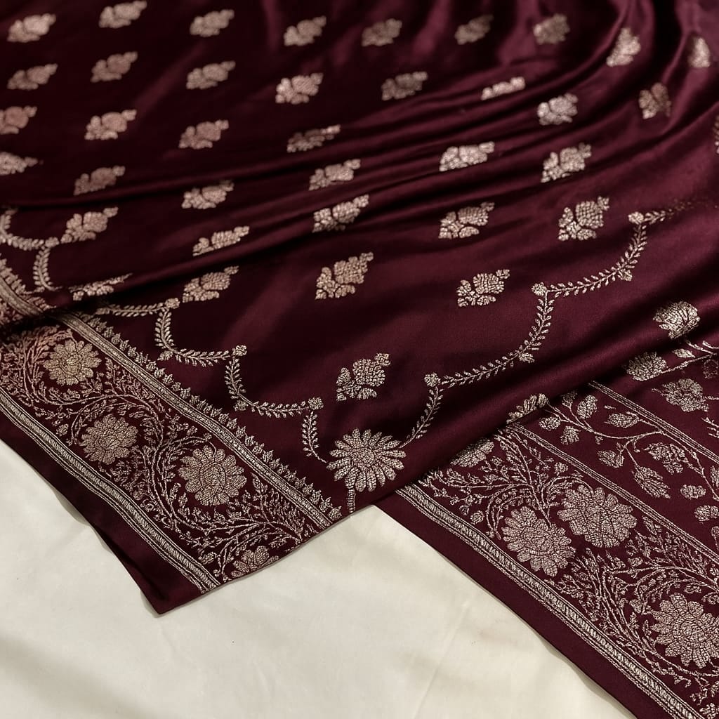 Maroon fabric with intricate gold patterns on a white background
