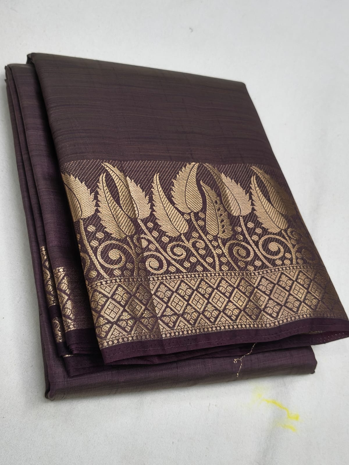 Brown saree with gold leaf patterns on a white background