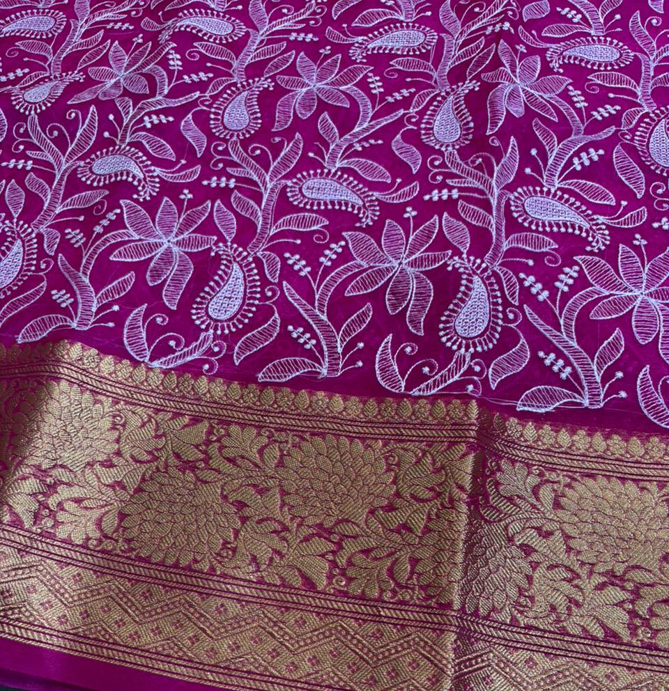 Purple saree with white floral patterns and gold border on a green surface