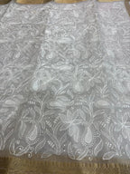 White lace fabric with floral patterns on a gold border