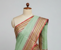 Green saree with a red and gold border on a mannequin against a gray background