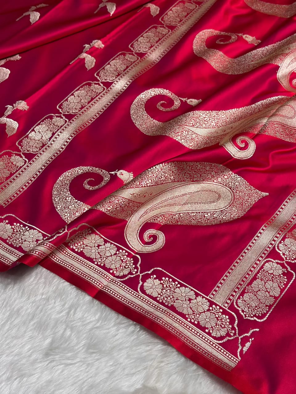 Red fabric with intricate white embroidery on a textured surface