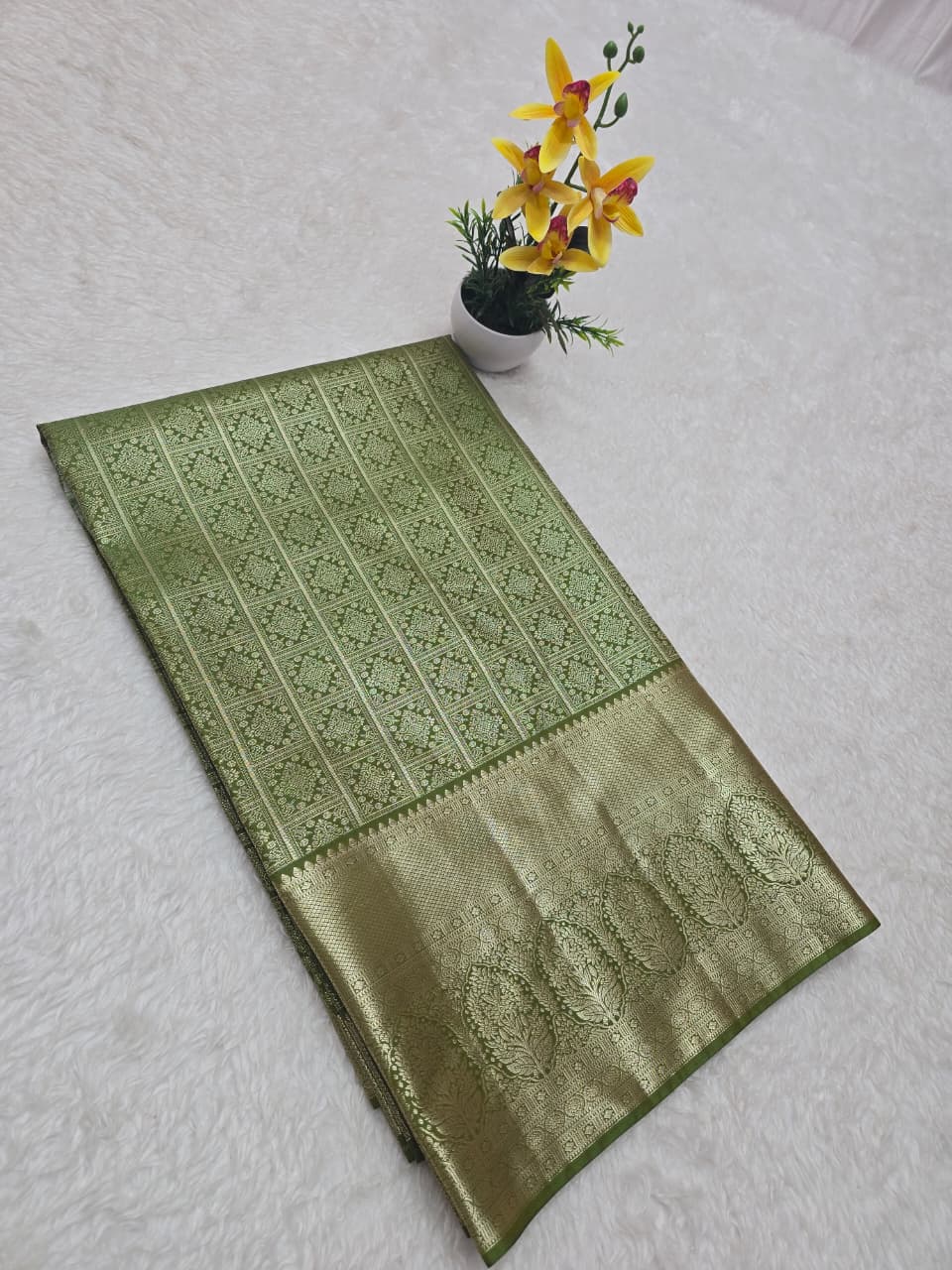 Green patterned fabric on a white surface with a small potted plant.