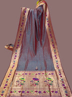 Traditional saree with intricate patterns on a table with stacks of fabric in the background