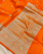 Bright orange Banarasi silk saree with intricate silver zari woven borders and small floral motifs.