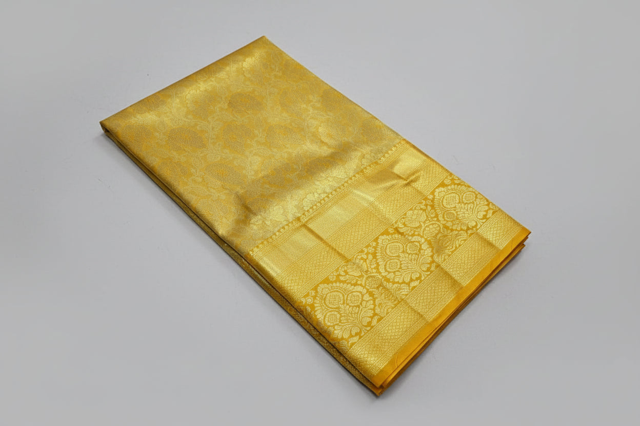 Gold fabric on a white surface with a small potted plant and yellow flowers.