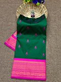 Green saree with pink border on a textured surface