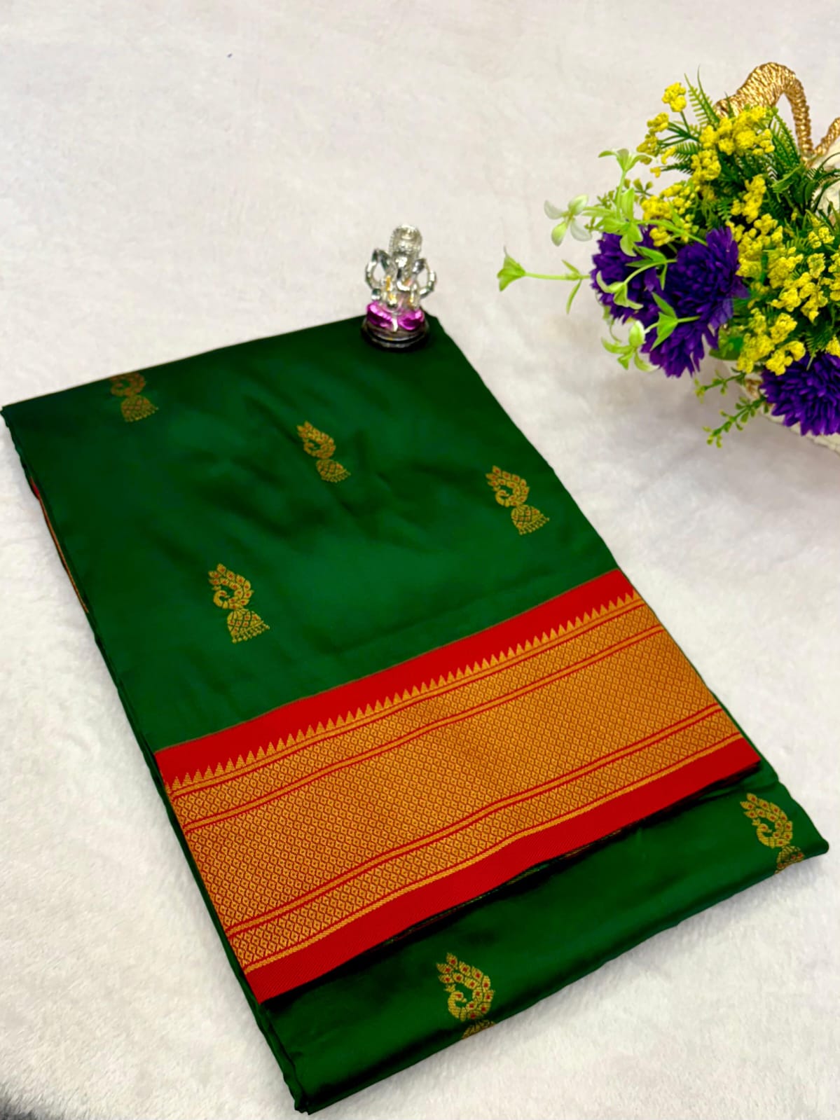 Green saree with gold and red border on a white background
