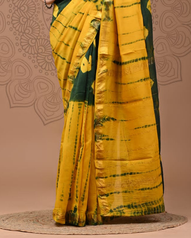 Woman wearing a green and yellow saree with a decorative background