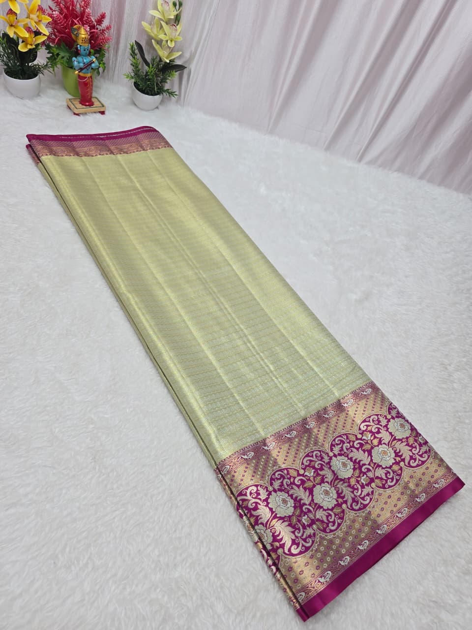 Light green saree with pink and gold border on a white background