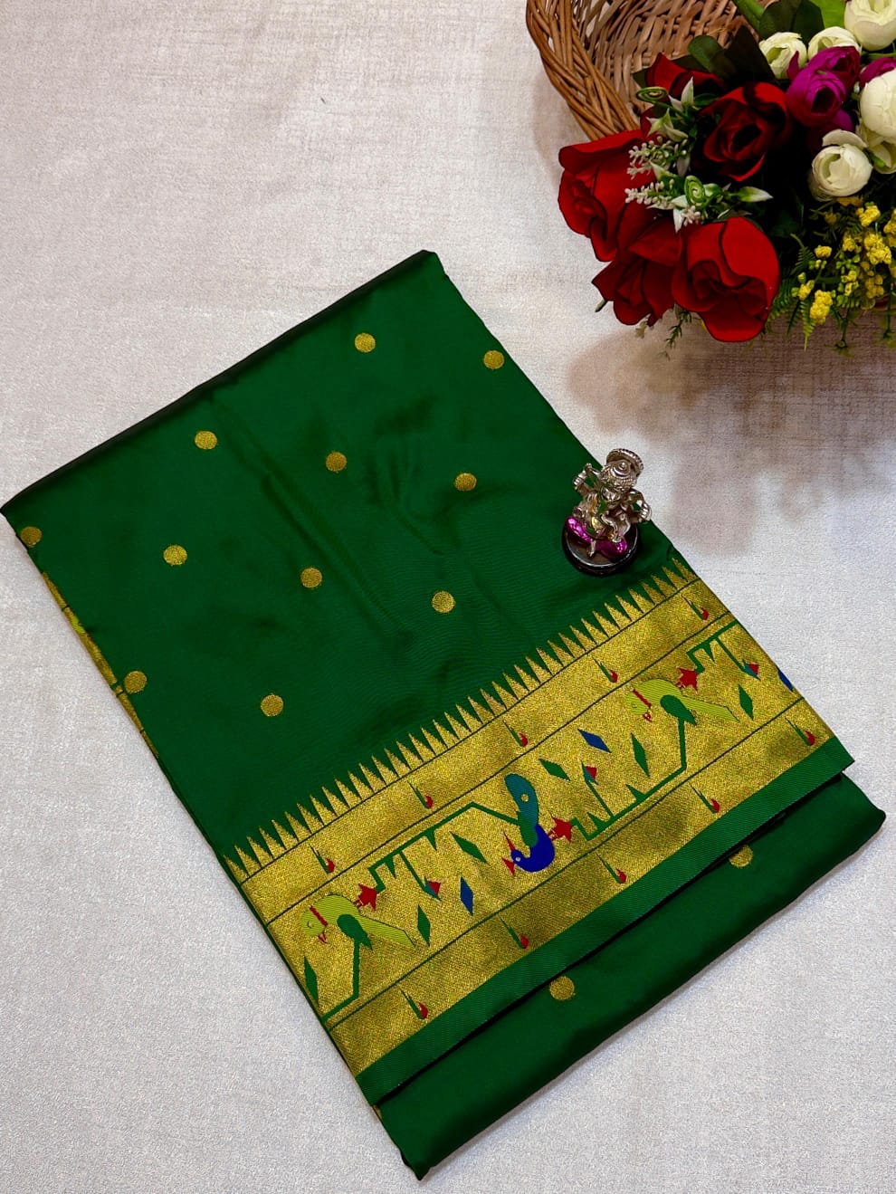 Green saree with gold border and floral decoration on a white background