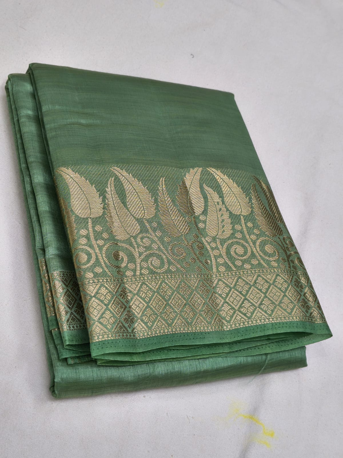 Green saree with intricate gold patterns on a white background