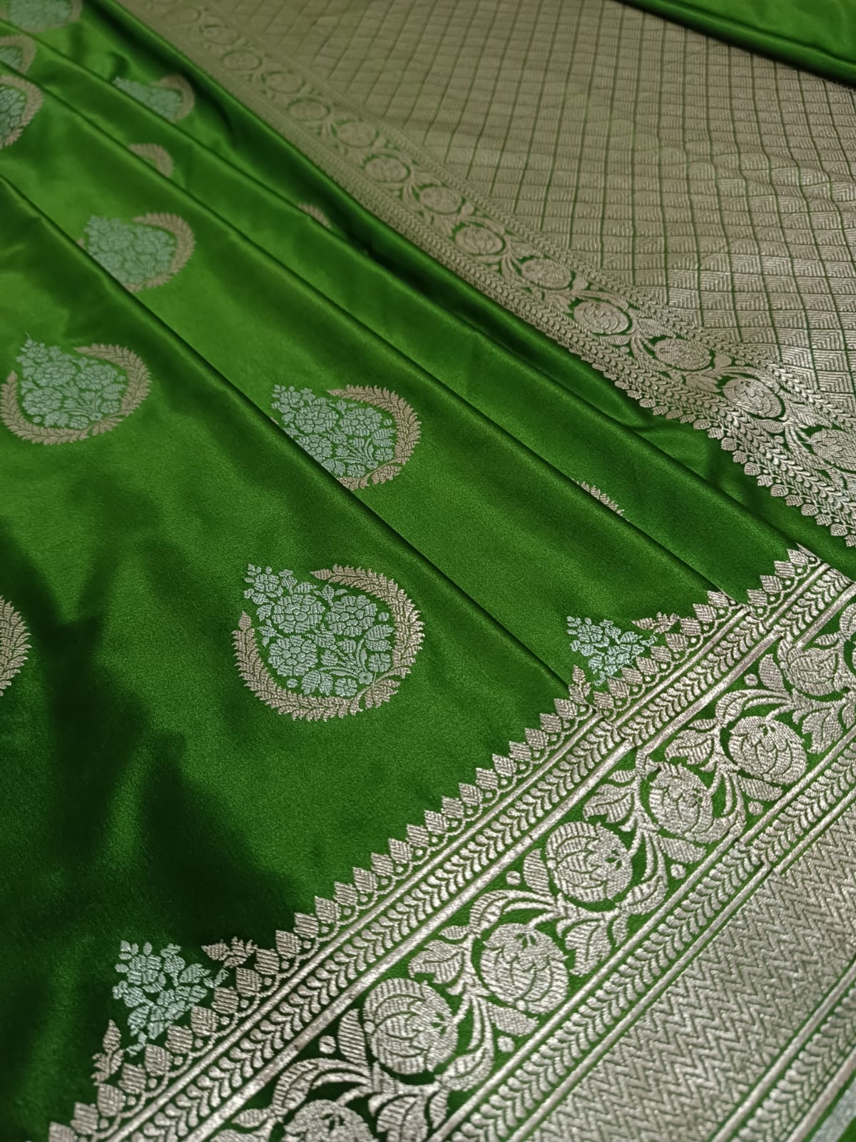 Green fabric with intricate white patterns on a textured surface