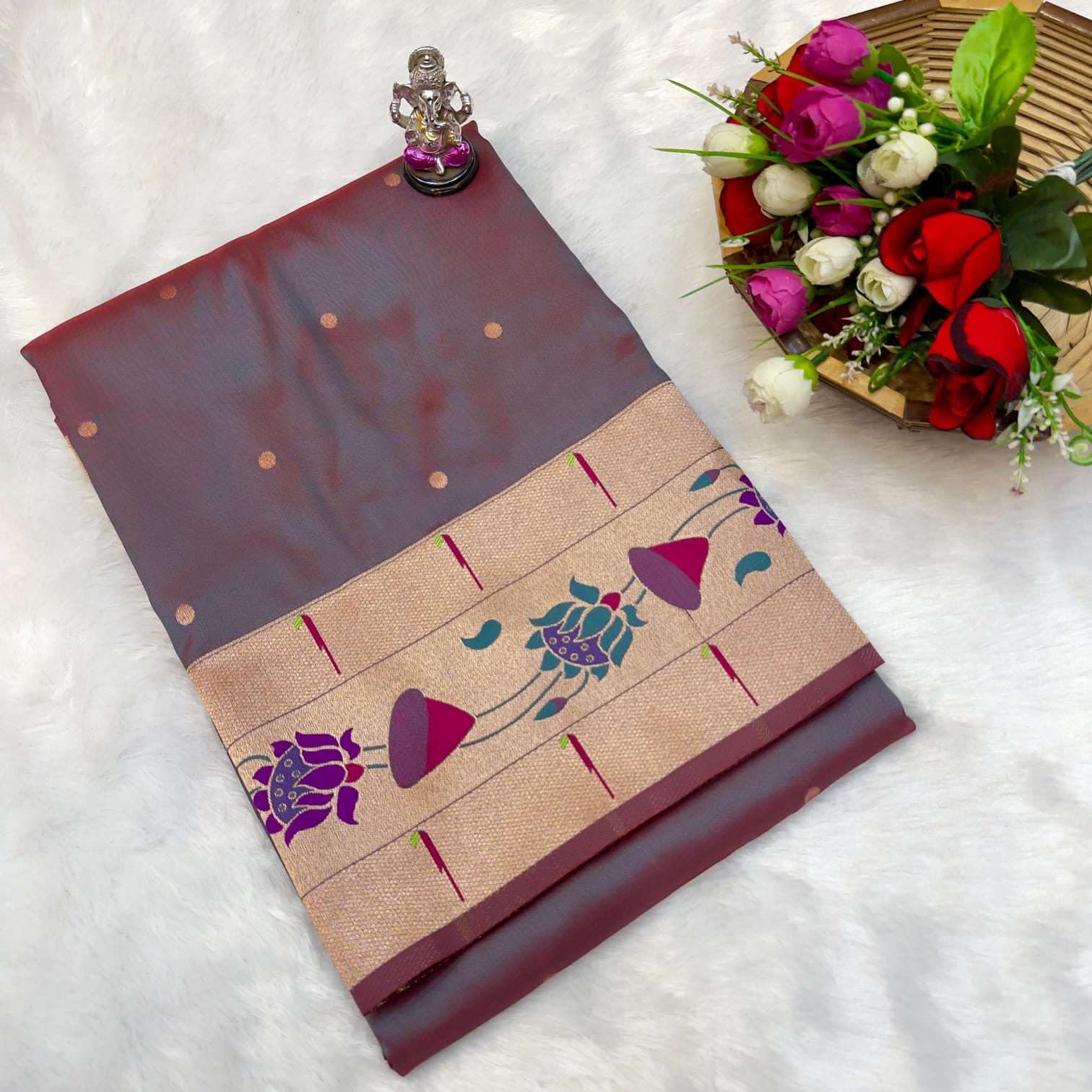 Decorative folded fabric with floral patterns on a white surface with flowers and a statue.