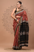 Woman wearing a red and black saree with white patterns on a beige background