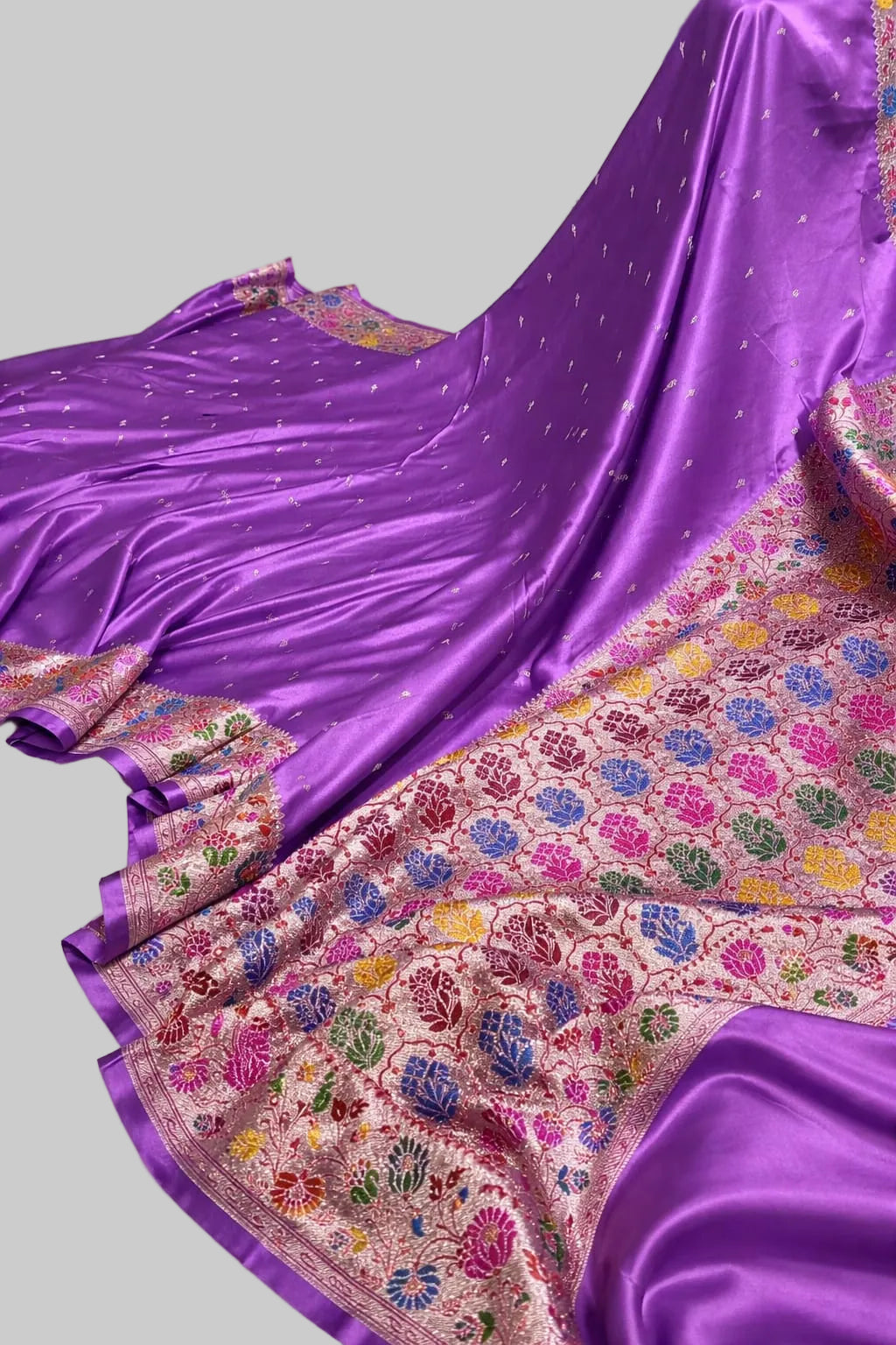 Purple saree with a colorful floral pattern on a white surface