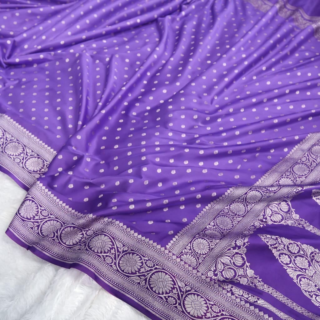 Purple saree with white polka dots and intricate silver border on a white background